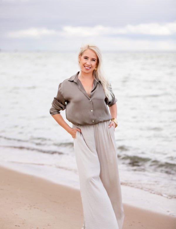 Svetlana Ambre дружелюбно улыбается, стоя на пляже у моря