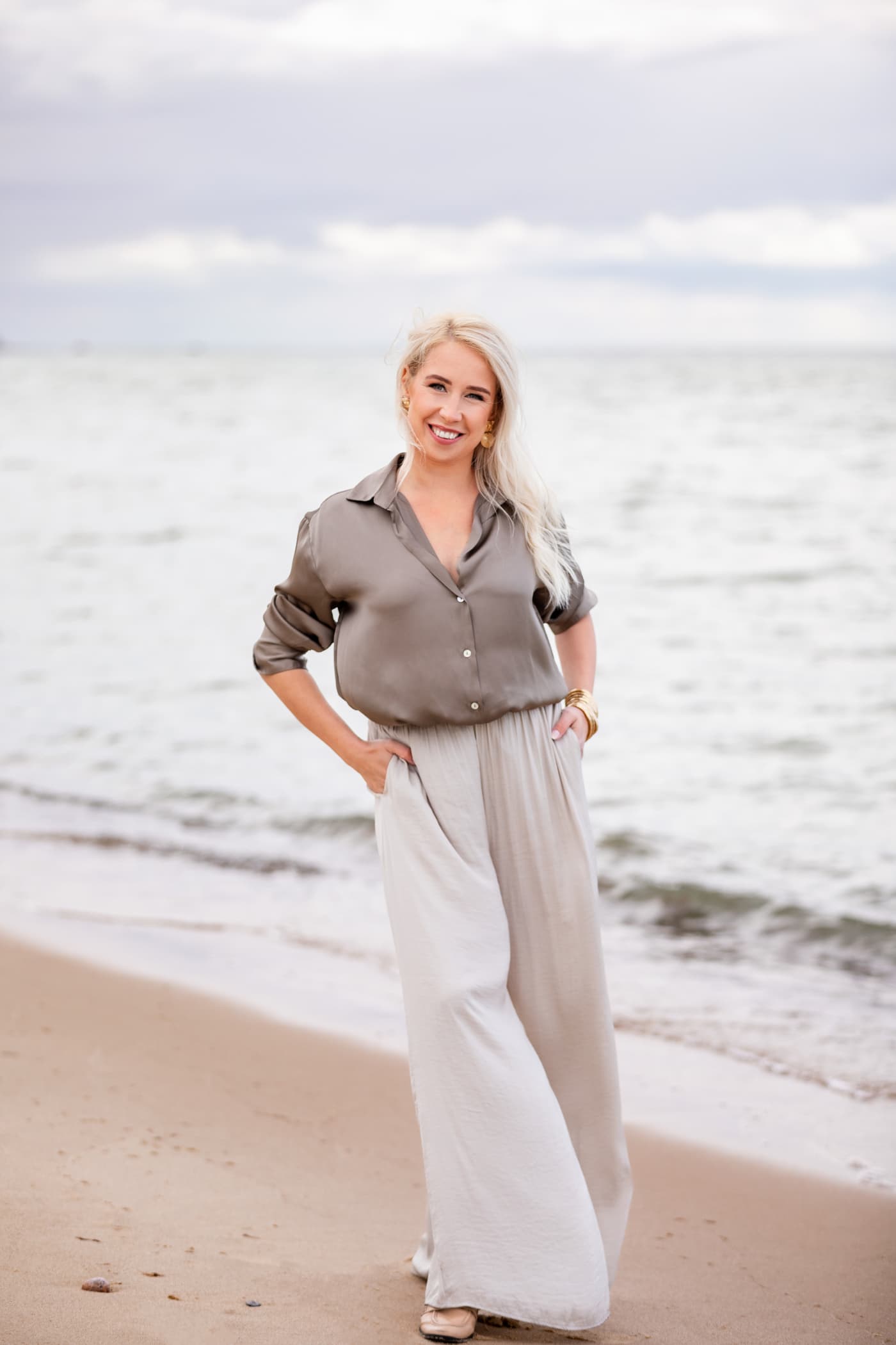 Svetlana Ambre дружелюбно улыбается, стоя на пляже у моря